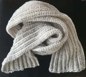A white crocheted scarf sits on a black background.