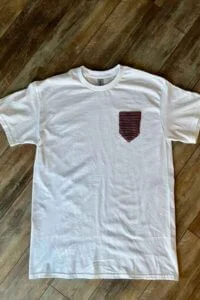 A white t-shirt with a crocheted pocket attached.